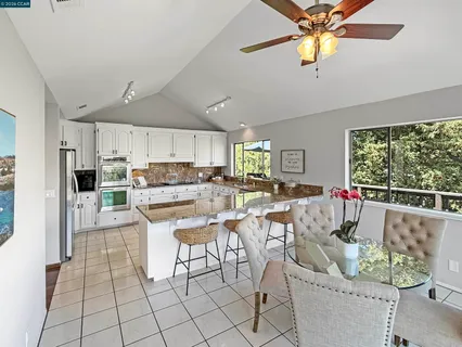 a kitchen with stainless steel appliances kitchen island granite countertop a refrigerator a stove a microwave oven a dining table and chairs with wooden floor