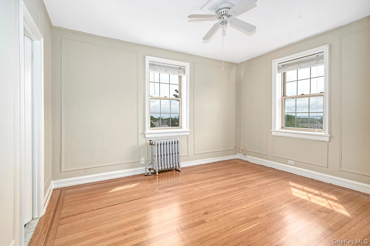 151 Centre Avenue, Unit 5D New Rochelle, NY 10805 - Photo 11 of 17 an empty room with wooden floor fan and windows