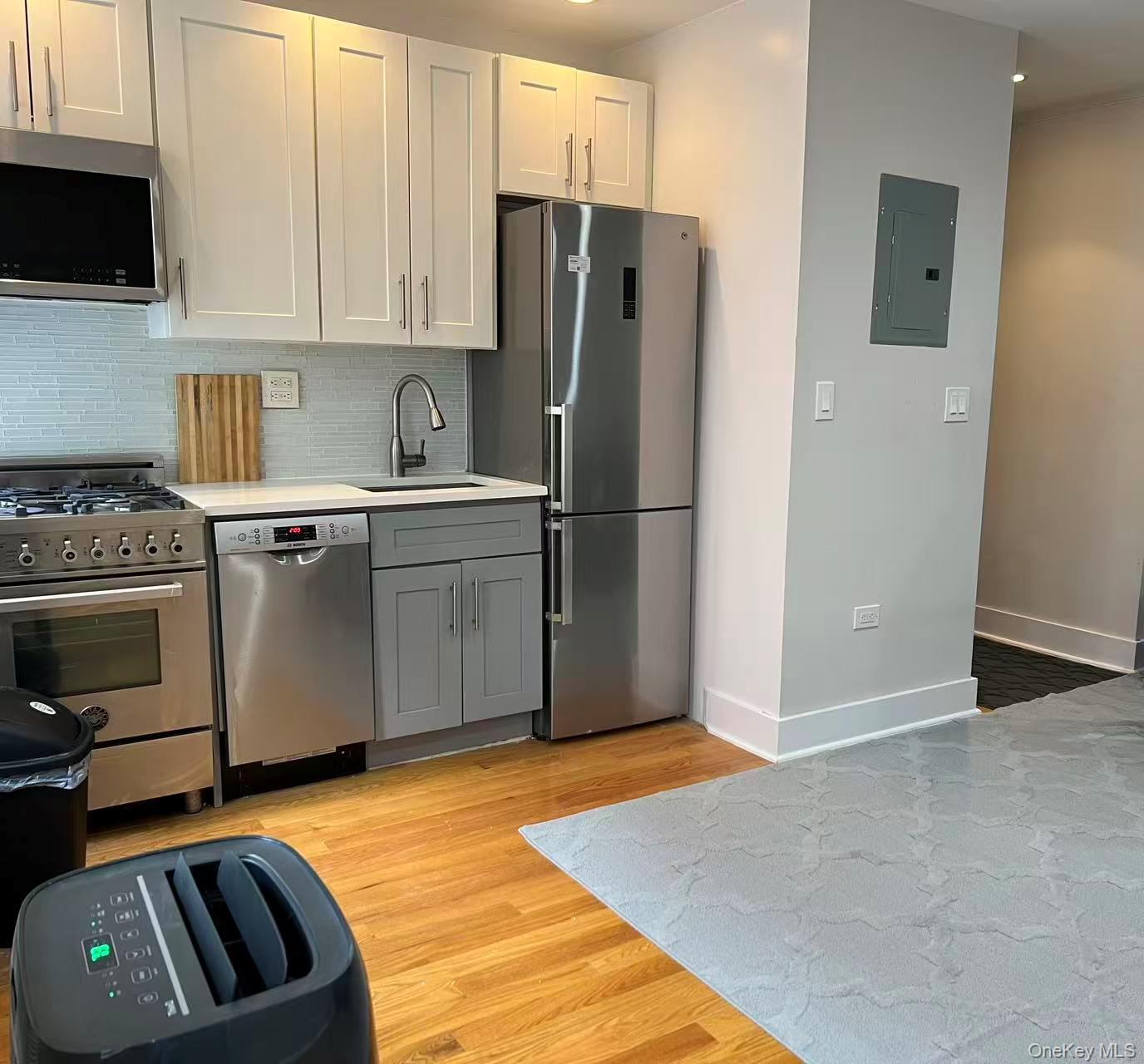 42-22 Ketcham Street, Unit 3E Queens, NY 11373 - Photo 4 of 8 a kitchen with stainless steel appliances granite countertop a refrigerator a stove a sink and a microwave