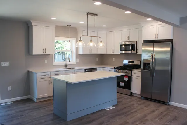 a kitchen with kitchen island granite countertop a sink a counter space appliances and cabinets
