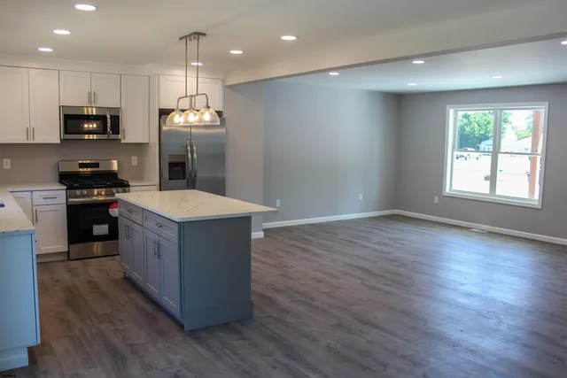 a large kitchen with stainless steel appliances granite countertop a large counter top and wooden floors