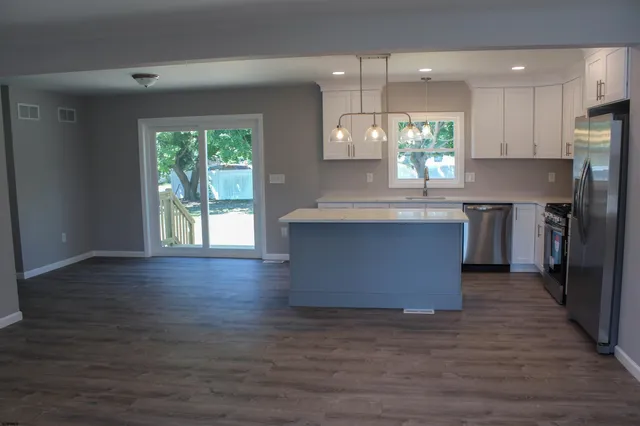 an open kitchen with wooden floor and stainless steel appliances