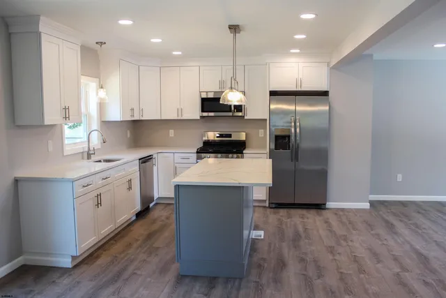 a kitchen with kitchen island a white cabinets and stainless steel appliances