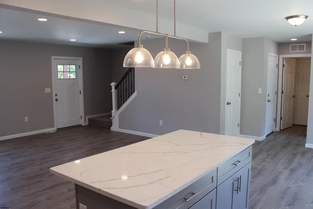 a kitchen with stainless steel appliances granite countertop a kitchen island a stove and a wooden floors
