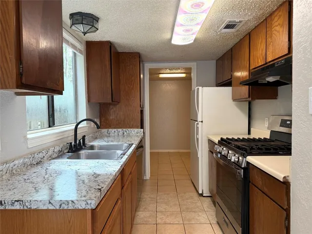 a kitchen with granite countertop a sink stove and refrigerator