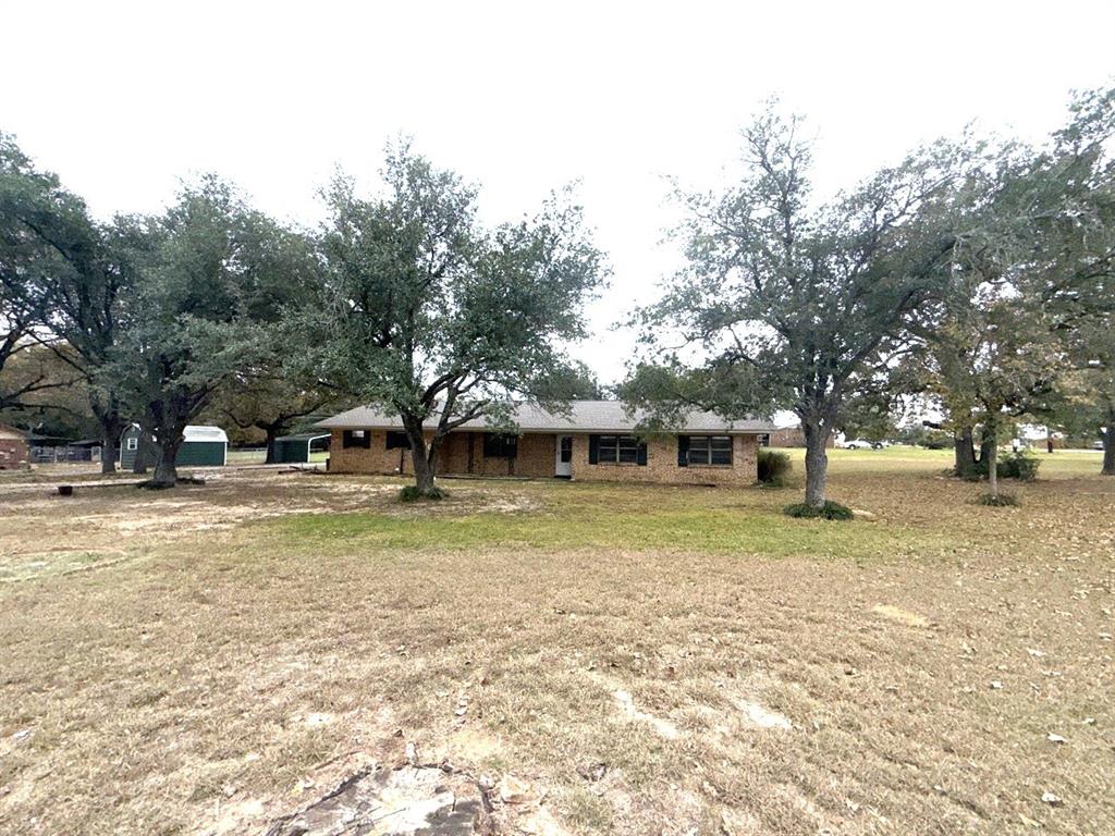 a view of a house with a yard and large trees