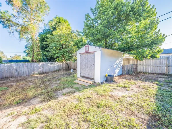 a view of a backyard with large trees and wooden fence