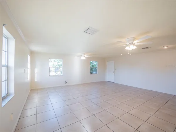an empty room with windows and fan