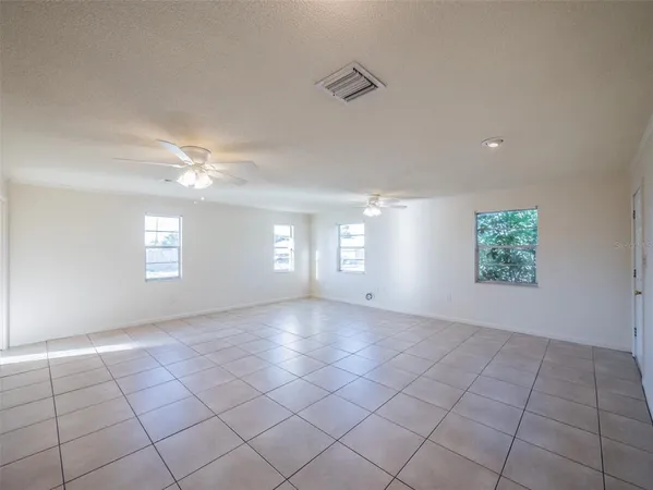 an empty room with windows and fan
