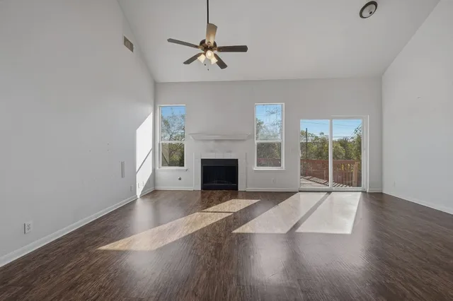 a view of an empty room with wooden floor fireplace and a window