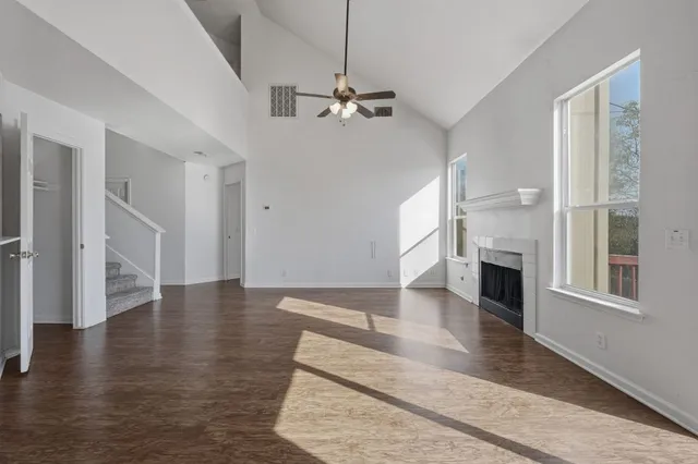 an empty room with wooden floor fireplace and windows