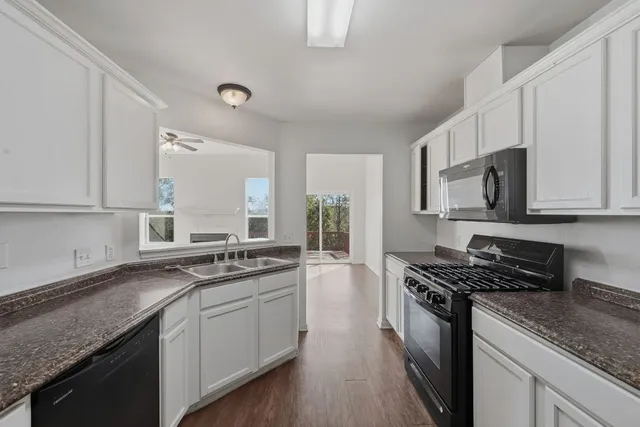 a kitchen with stainless steel appliances granite countertop a sink stove cabinets and microwave