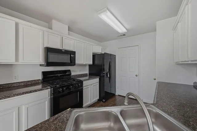 a kitchen with granite countertop a sink stainless steel appliances and white cabinets