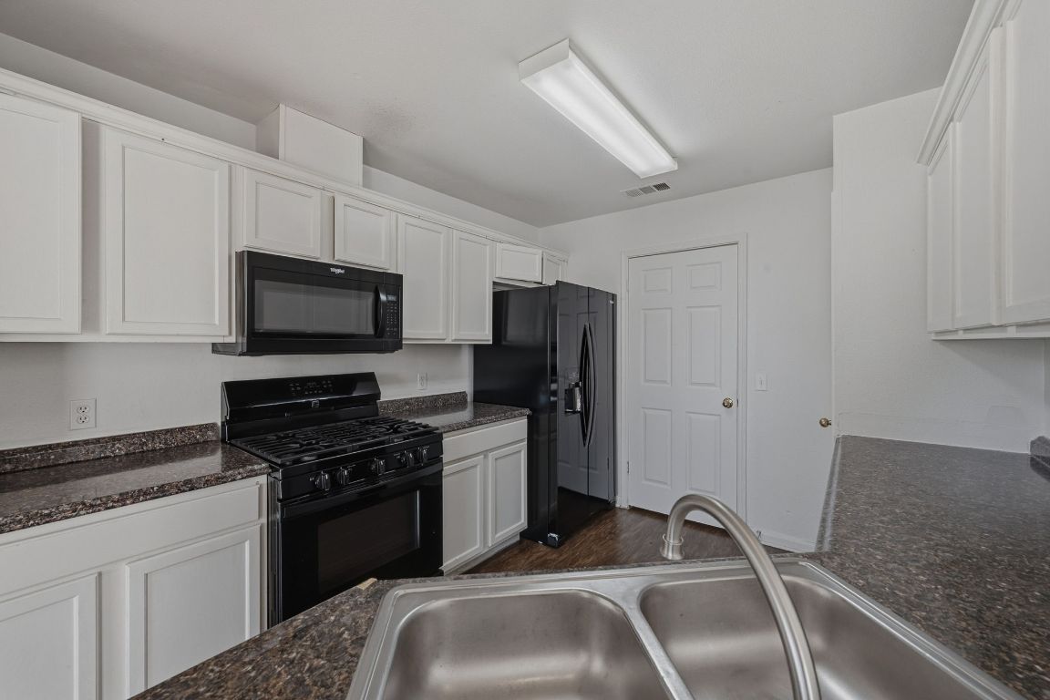 5237 Coppermead Lane Austin, TX 78754 - Photo 4 of 25 a kitchen with granite countertop a sink stainless steel appliances and white cabinets