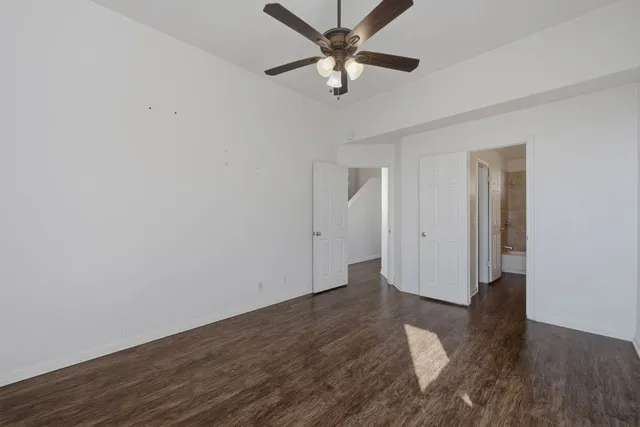 an empty room with wooden floor fan and windows