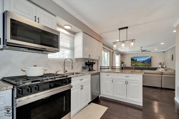 a kitchen with stainless steel appliances a sink a stove top oven a sink dishwasher and white cabinets