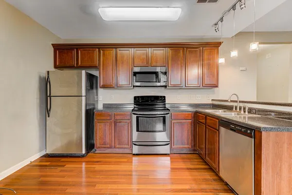 a kitchen with granite countertop a refrigerator and a stove top oven