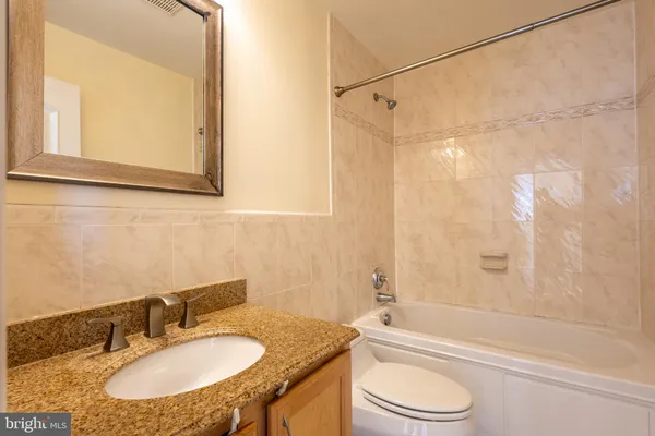 a bathroom with a granite countertop sink toilet a mirror and a shower