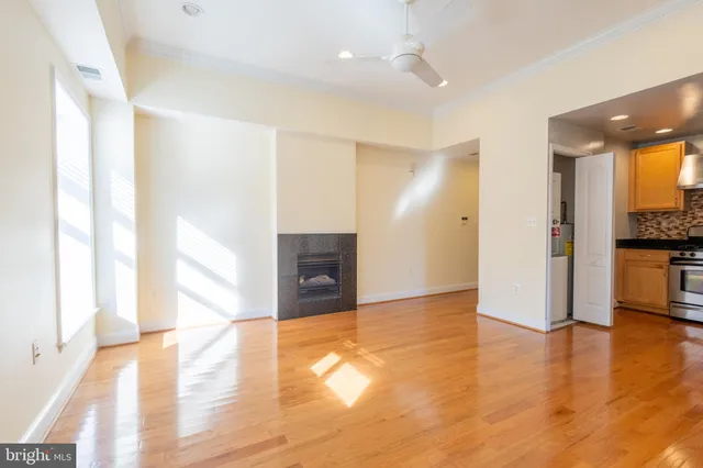a view of an empty room with wooden floor and a window