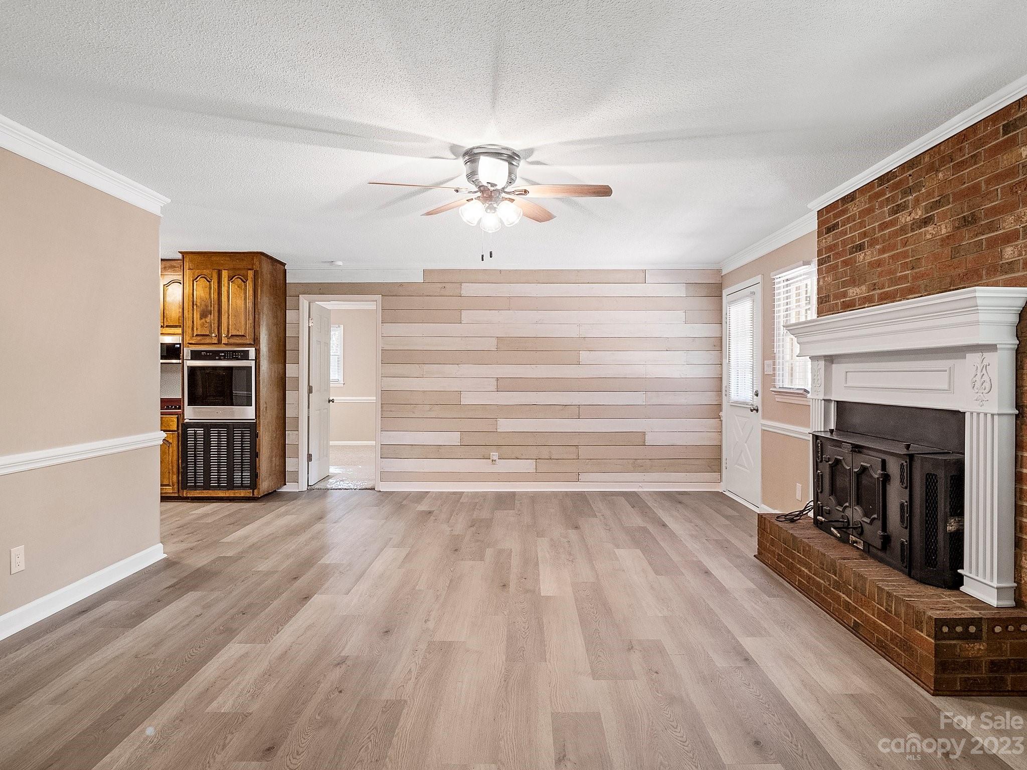 807 Red Cedar Lane Monroe, NC 28110 - Photo 11 of 34 a view of a livingroom with wooden floor a fireplace a ceiling fan and windows