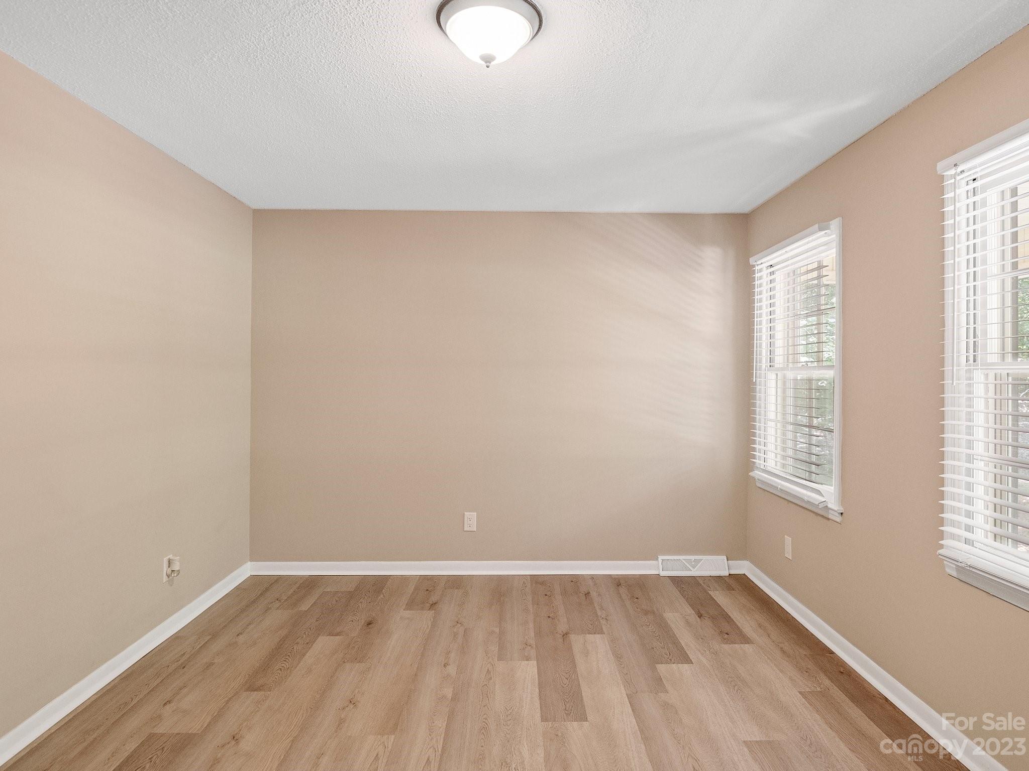 807 Red Cedar Lane Monroe, NC 28110 - Photo 9 of 34 an empty room with wooden floor and windows