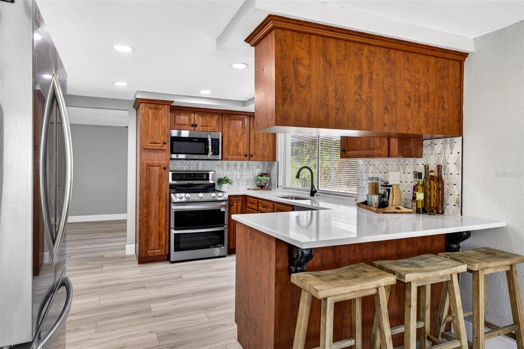 12415 Stagecoach Lane Hudson, FL 34667 - Photo 14 of 51 a kitchen with stainless steel appliances a stove a sink and a refrigerator with wooden floor