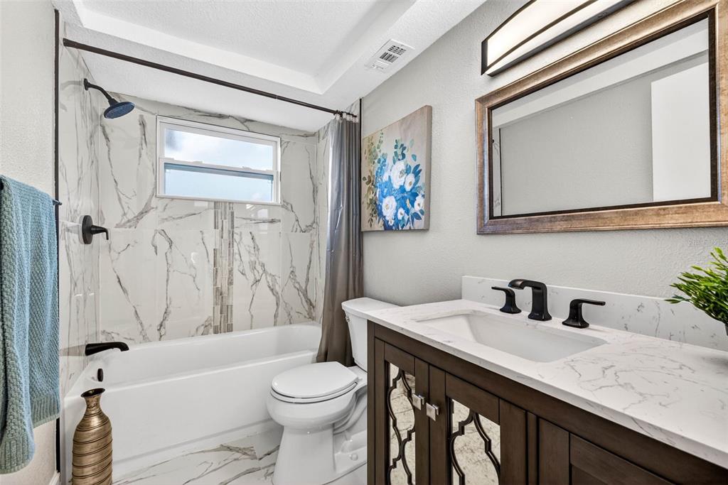 12415 Stagecoach Lane Hudson, FL 34667 - Photo 24 of 51 a bathroom with a granite countertop sink toilet a mirror a bathtub and shower