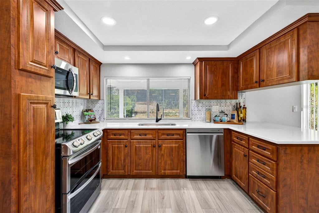 12415 Stagecoach Lane Hudson, FL 34667 - Photo 10 of 51 a kitchen with stainless steel appliances granite countertop wooden cabinets a sink a stove a refrigerator and island with wooden floor