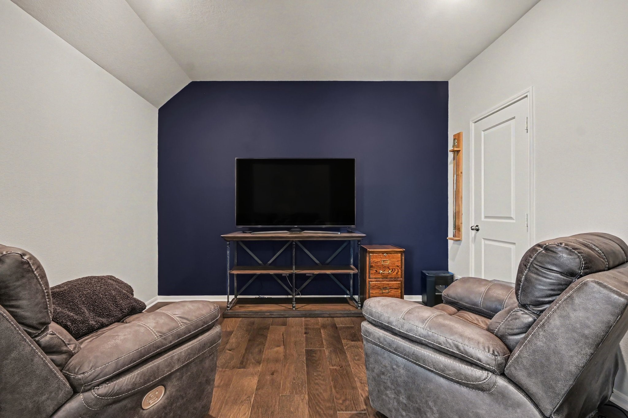 641 Kickapoo Court Webster, TX 77598 - Photo 24 of 39 Cozy media room featuring a dark accent wall, and warm wood flooring. Perfect for relaxing or entertaining.