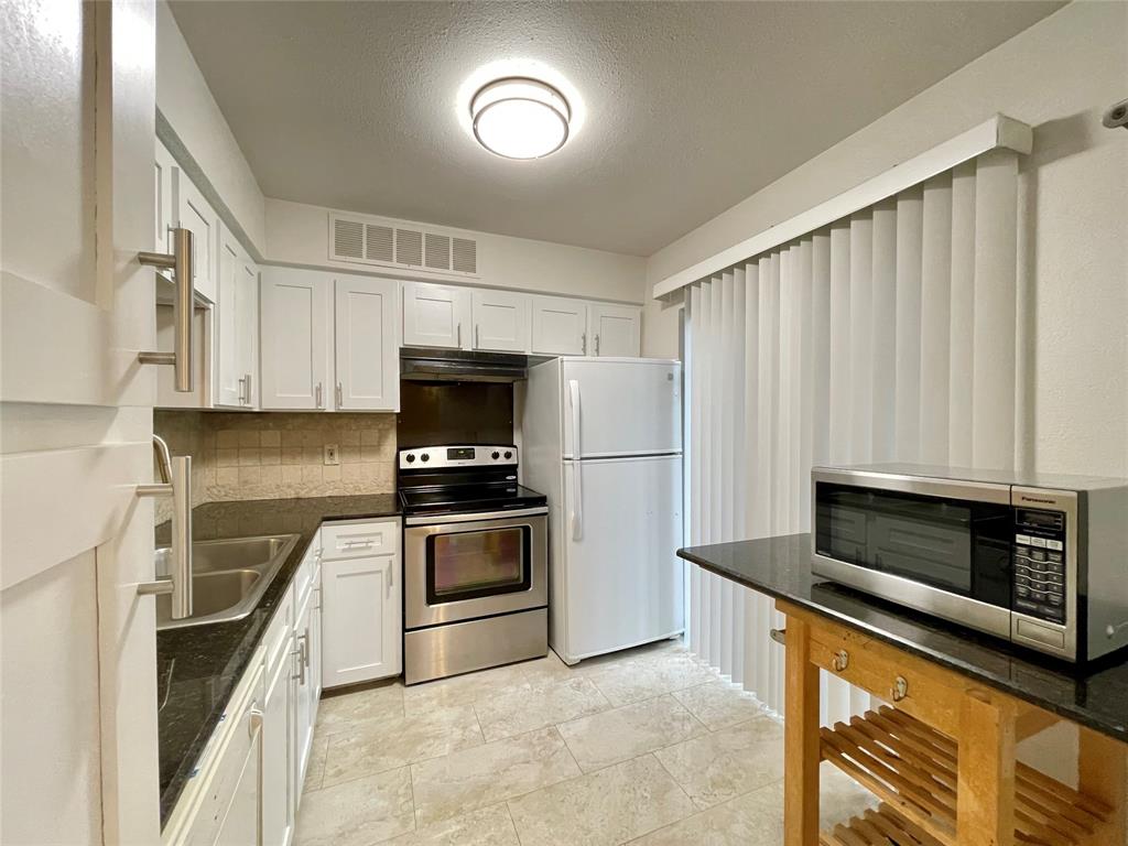 336 Melrose Drive, Unit 5C Richardson, TX 75080 - Photo 9 of 22 a kitchen with granite countertop a stove a sink and a microwave