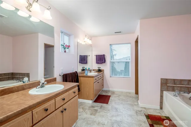 a spacious bathroom with a granite countertop sink mirror and bathtub