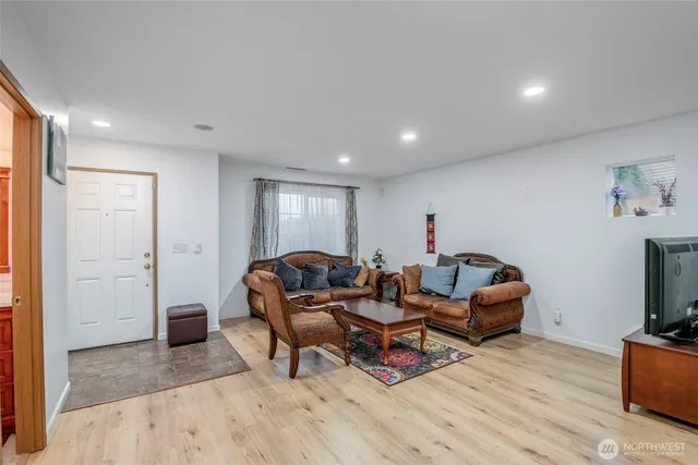 a living room with furniture a flat screen tv and a refrigerator