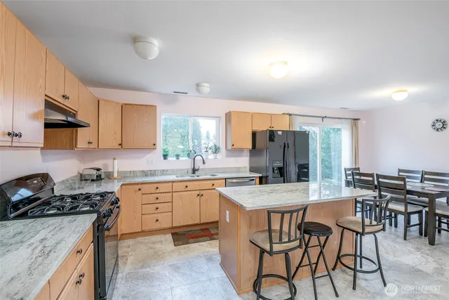 a kitchen with stainless steel appliances granite countertop a stove a sink dishwasher a stove a refrigerator with a dining table and chairs