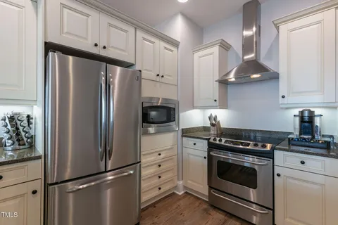 a kitchen with granite countertop a refrigerator stove and cabinets