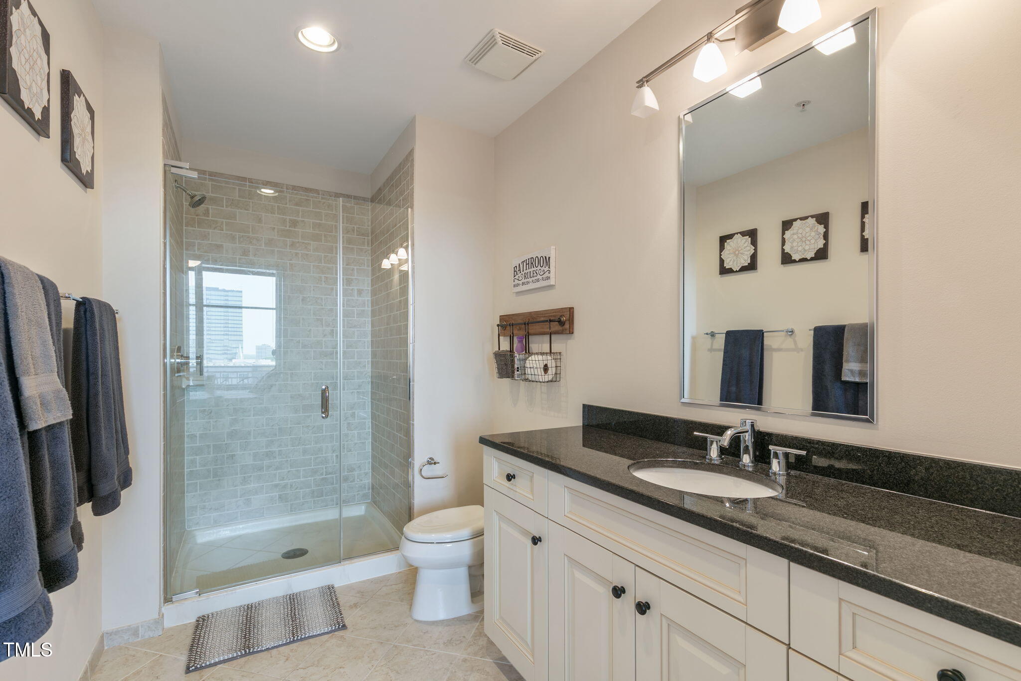 400 West North Street, Unit 1134 Raleigh, NC 27603 - Photo 16 of 39 a bathroom with a granite countertop sink a toilet a mirror and shower