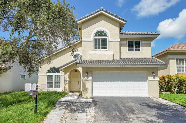 a front view of a house with a garden and trees