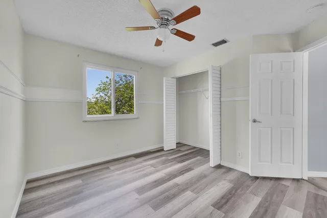 an empty room with wooden floor and ceiling fan
