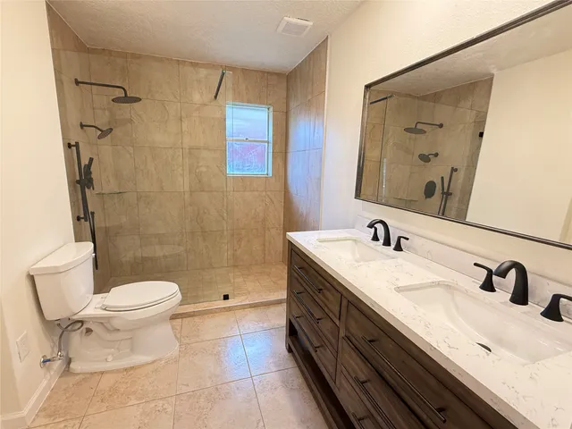 a bathroom with a double vanity sink toilet and a mirror