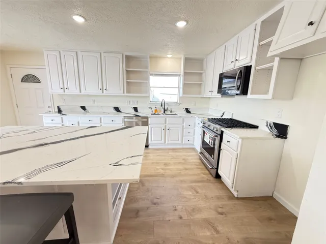 a kitchen with white cabinets sink and stove