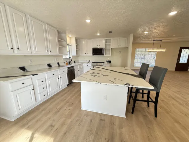 a kitchen with white cabinets and chairs