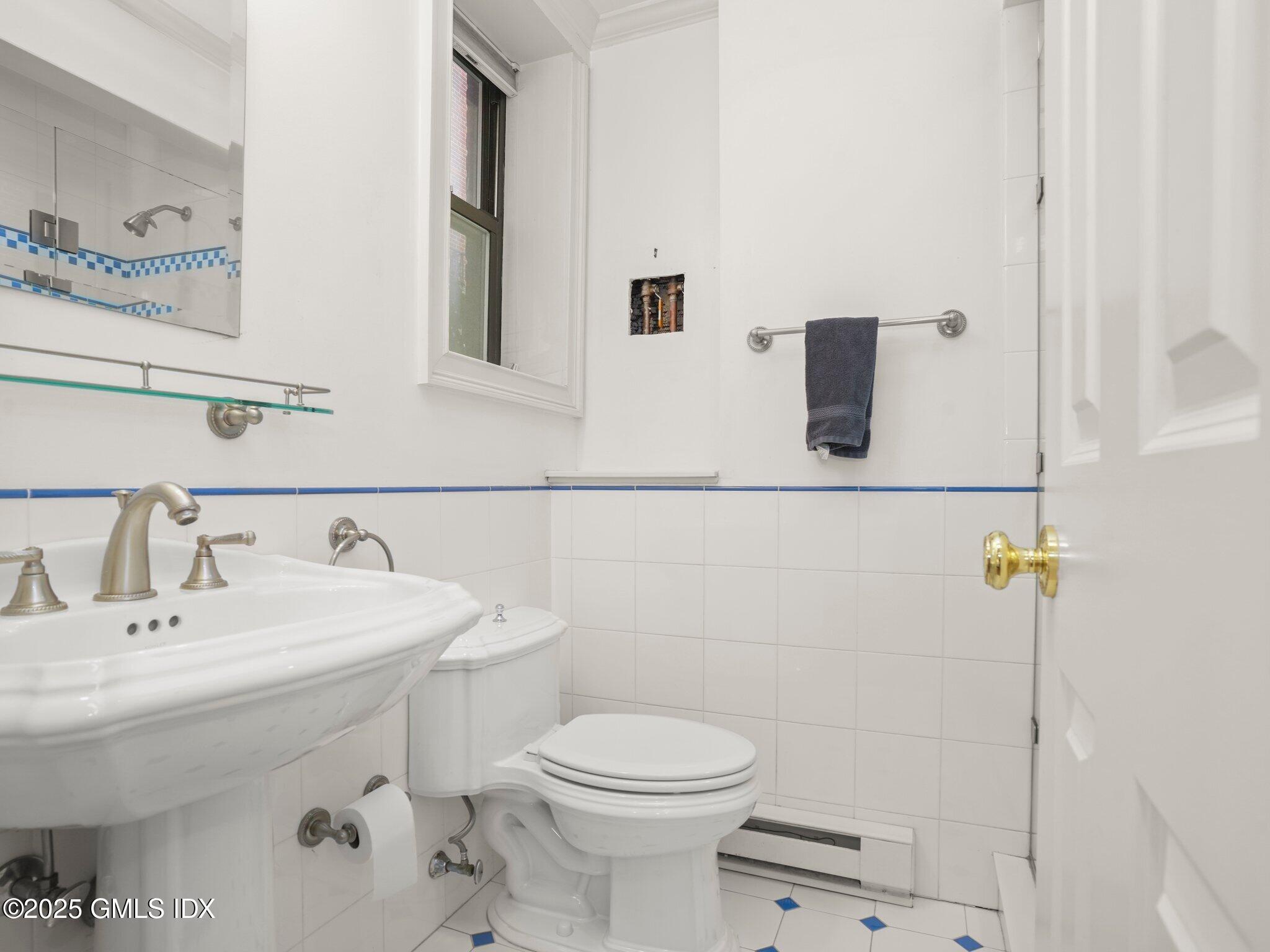 40 West Elm Street, Unit 1M Greenwich, CT 06830 - Photo 11 of 16 a bathroom with a toilet a sink and mirror