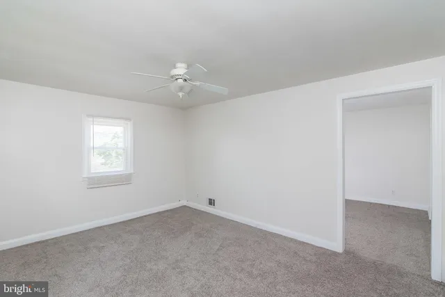an empty room with a window and a ceiling fan