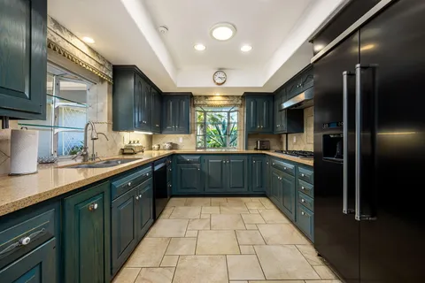 a large kitchen with stainless steel appliances granite countertop a refrigerator and a sink