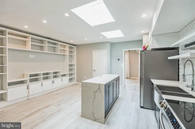 a kitchen with stainless steel appliances kitchen island wooden floors and white cabinets