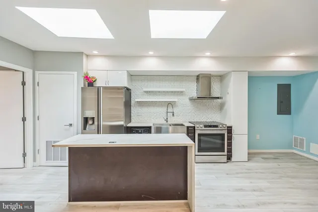 a large kitchen with stainless steel appliances kitchen island granite countertop a sink and cabinets