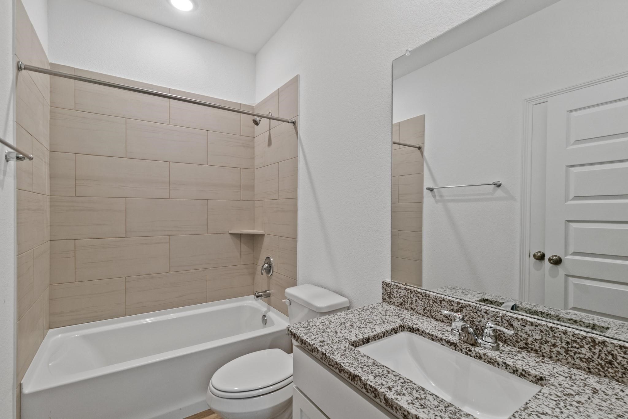 23018 Forebear Drive Katy, TX 77493 - Photo 22 of 25 a bathroom with a granite countertop bathtub toilet sink and shower