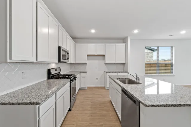 a kitchen with stainless steel appliances granite countertop a sink stove and cabinets