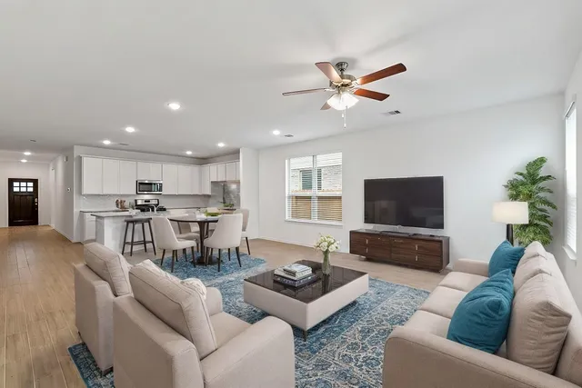 a living room with furniture kitchen view and a flat screen tv
