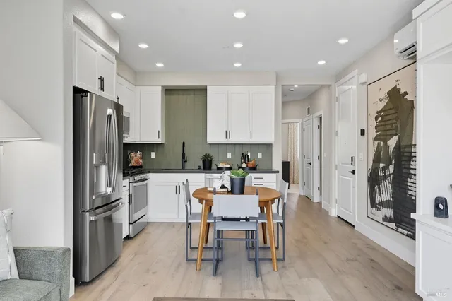a kitchen with a refrigerator a dining table and chairs