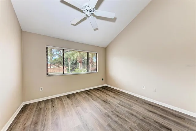 an empty room with wooden floor fan and windows